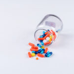 high angle view pills coming out of jar on white background. horizontal